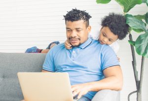 Father working while son looks over his shoulder