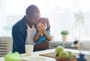 Father kissing son eating breakfast