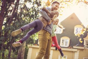 Father spinning his daughters around in front of their house